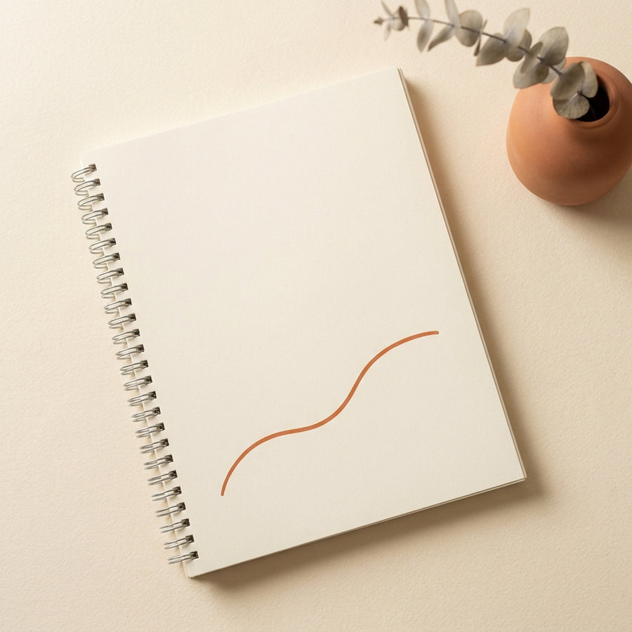 Closed printable workbook on warm cream surface, soft side-light, hands resting on cover