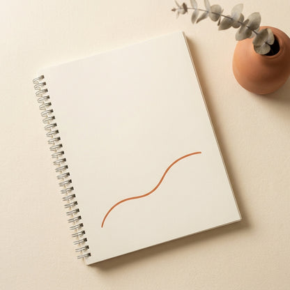 Closed printable workbook on warm cream surface, soft side-light, hands resting on cover